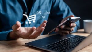 Pessoa fazendo vendas online pelo celular, com ícones de carrinhos de compras sobre a imagem, destacando a importância do e-commerce no Brasil.